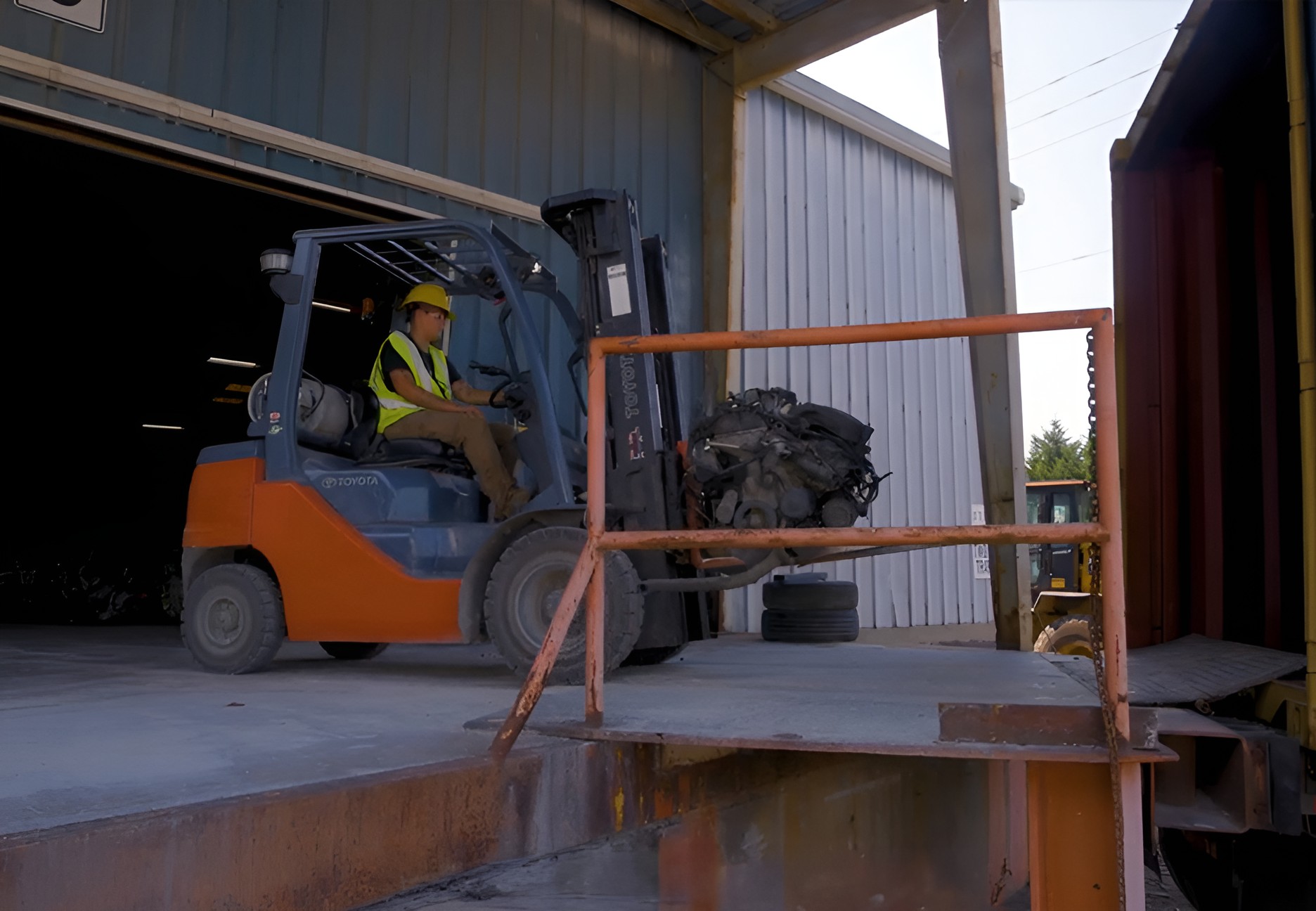 forklift worker carrying bin of catalytic converters into a truck